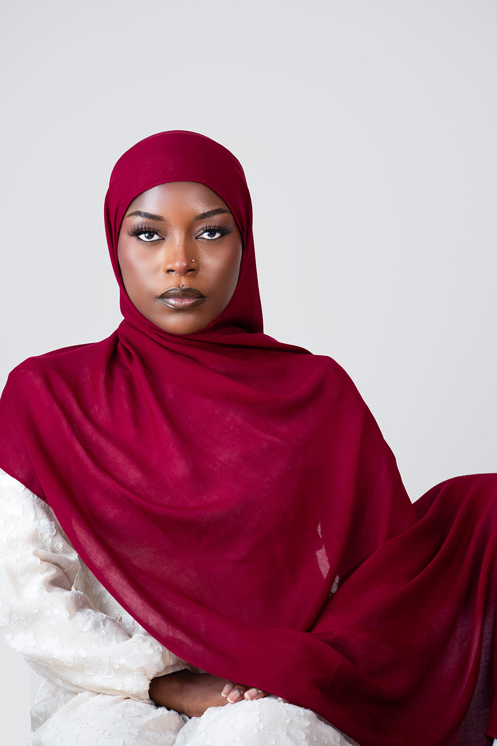 Woman wearing a red hijab against a white background