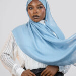 Woman wearing a light blue hijab against a white background