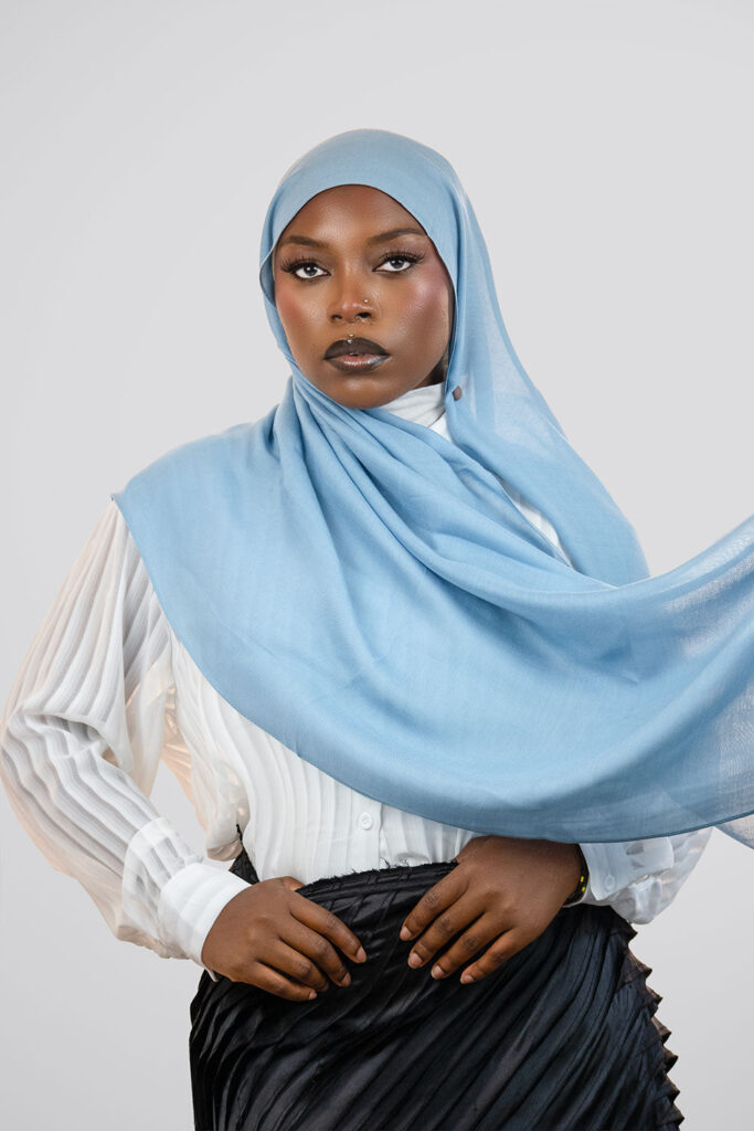 Woman wearing a light blue hijab against a white background